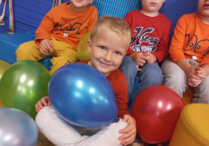 Chłopiec z balonem pozuje do zdjęcia grupowego.